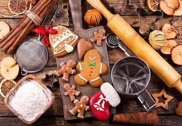 Comida navideña. Galletas caseras de hombre de jengibre con ingredientes para cocinar y utensilios de cocina navideños en la mesa de madera, vista superior