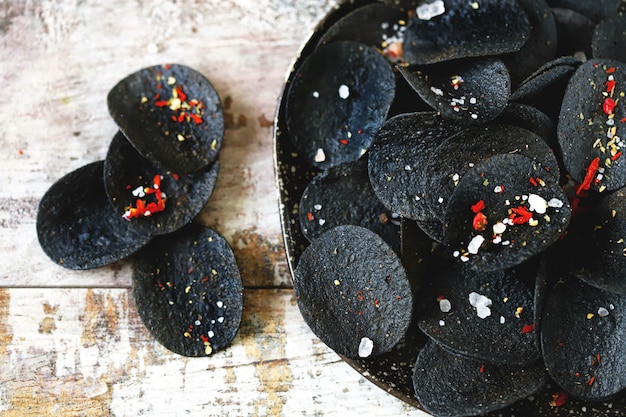 Comida negra Fichas negras con especias en un plato. Tendencia de comida negra.