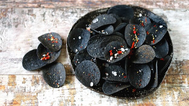 Comida negra Fichas negras con especias en un plato. Tendencia de comida negra.