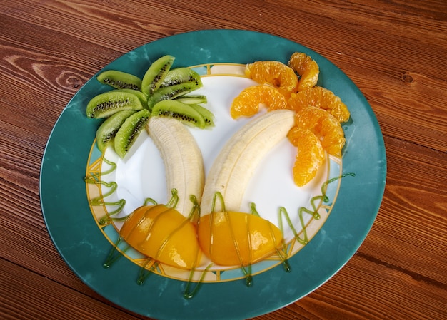 Comida para niños. Postre de frutas para niño con kiwi, plátano y naranja