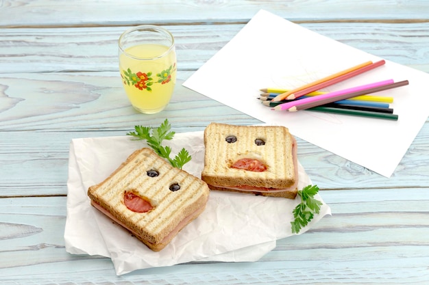 Comida para niños Sándwiches calientes y un vaso de jugo en un primer plano de la mesa de madera