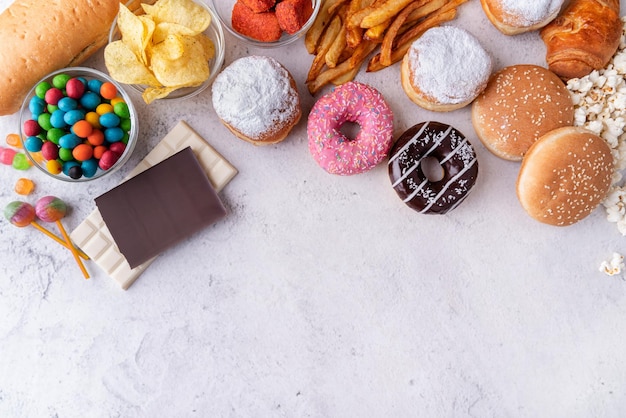 Foto comida no saludable y comida rápida con rosquillas, hamburguesas de chocolate y dulces vista superior con espacio para copiar