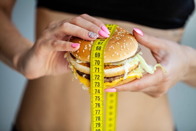 Foto comida nociva la elección entre comida maliciosa y deporte. hermosa joven en una dieta. el concepto de belleza y salud.