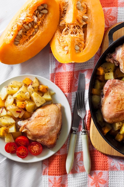 Comida en una olla: muslos y piernas de pollo con papas y calabaza al horno en una sartén de hierro fundido