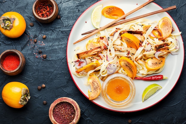 Comida oriental, salada com macarrão, caqui e berinjela. Salada asiática saudável