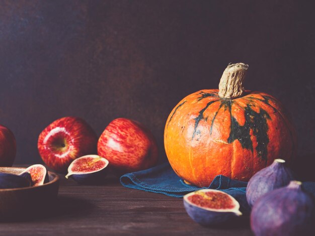 Comida de otoño bodegón con frutas y verduras de temporada como calabazas, manzanas rojas e higos en una mesa