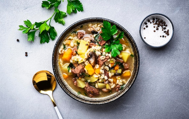 Comida de otoño Sopa caliente con champiñones de calabaza verduras carne de res y cebada Fondo de mesa gris vista superior