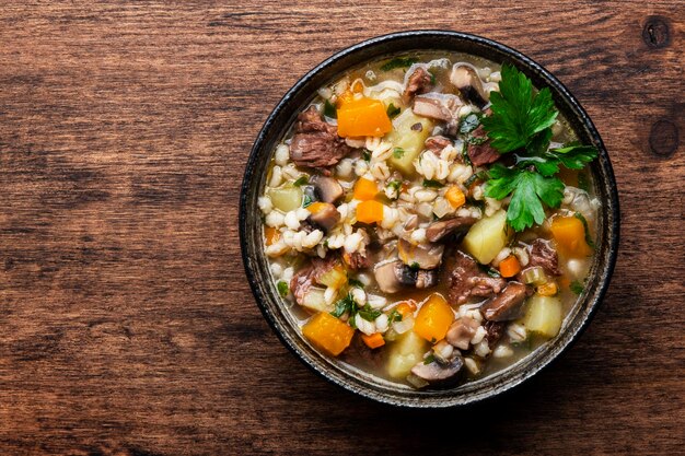 Comida de otoño Sopa caliente con champiñones de calabaza verduras carne de res y cebada Vista superior del fondo de la mesa de madera rústica