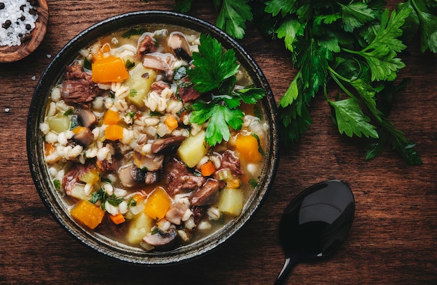 Comida de otoño Sopa caliente con champiñones de calabaza verduras carne de res y cebada Vista superior del fondo de la mesa de madera rústica