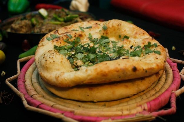 Comida paquistaní o nan paquistaní en una porción con pan nan o roti en placa de yute fondo negro