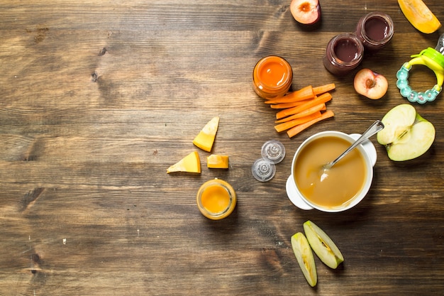 Comida para bebê Vários purês de frutas e vegetais em um fundo de madeira