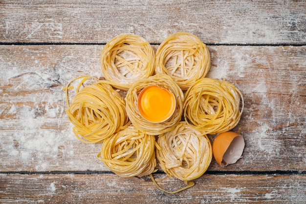 Comida de pasta fresca. Pasta italiana casera cocinada en una mesa de madera en un estilo rústico decorado con huevo y harina.