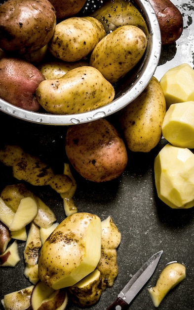 Foto comida de patata. el concepto de patatas peladas húmedas sobre la mesa de piedra.