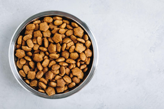 Comida para perros Comida seca para perros en un tazón sobre fondo de piedra gris