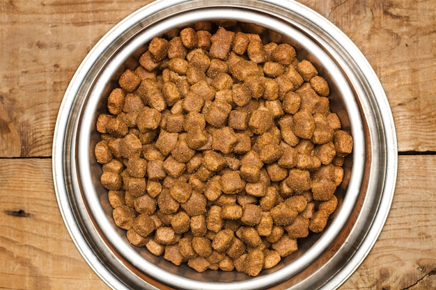 Comida para perros en un recipiente de acero inoxidable sobre una mesa de madera