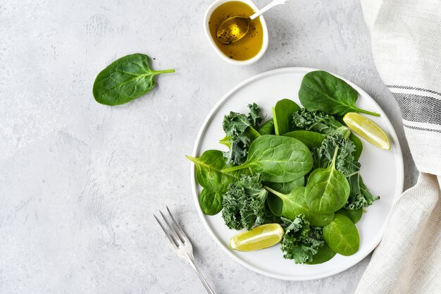 Comida plana, ensalada verde de espinaca orgánica y hojas de col con jugo de limón y aceite de oliva.