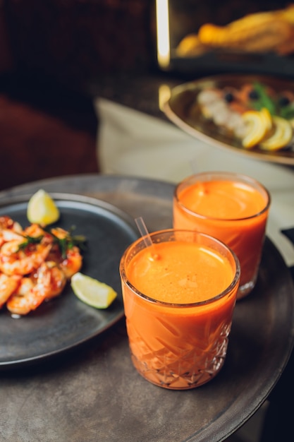 Comida en plato con dos vasos de bebidas.