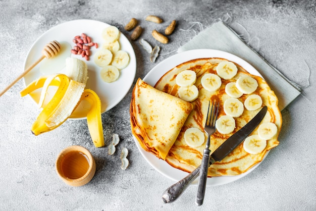 Comida, postre, pasteles, tortitas, pastel. Panqueques hermosos sabrosos con plátano y miel sobre un fondo concreto