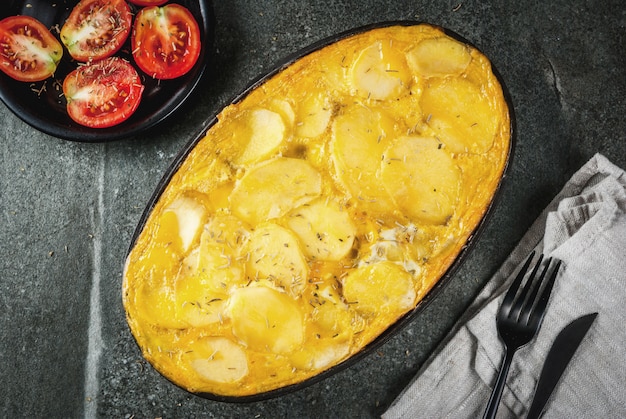 Comida. Prato tradicional Tortilla de patatas uma caçarola de batatas e ovos, sobre uma mesa de pedra preta.