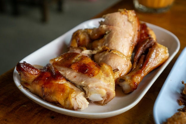 Foto comida de primer plano de pollo a la parrilla en un plato en una mesa de madera en un restaurante al aire libre