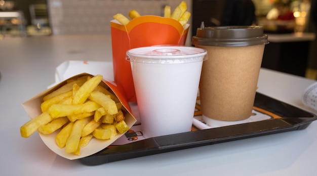 Comida rápida en una bandeja en un restaurante Papas fritas un vaso con un café batido