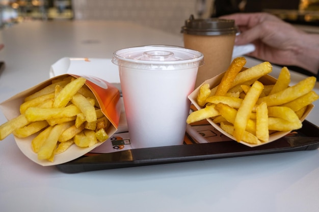 Comida rápida en una bandeja en un restaurante Papas fritas un vaso con un café batido