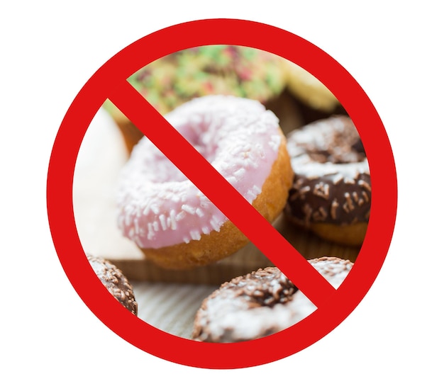 Foto comida rápida, dieta baja en carbohidratos, engorde y concepto de alimentación poco saludable - cierre de donuts glaseados detrás de ningún símbolo o signo de prohibición de barra invertida