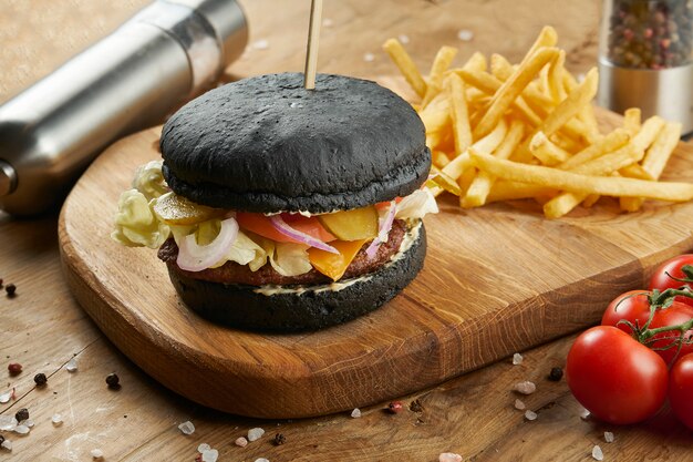 Comida rápida estadounidense clásica: jugosa hamburguesa con chuleta de ternera, tomates y queso cheddar con guarnición de ensalada y papas fritas. comida de la calle