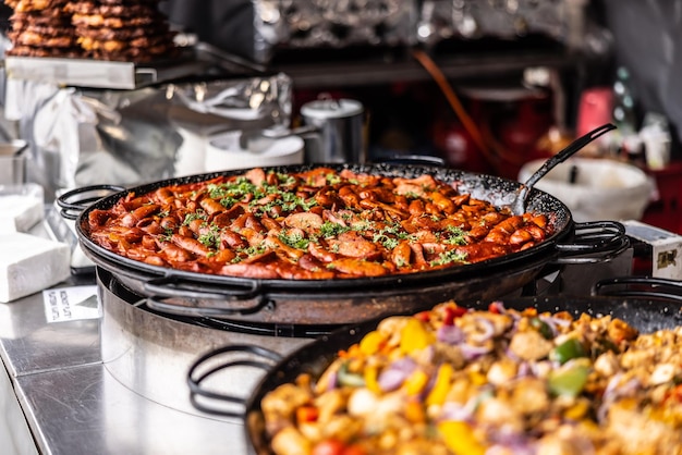 Comida reconfortante de la feria de la ciudad con estofado y embutidos ofrecidos a la venta en sartenes grandes