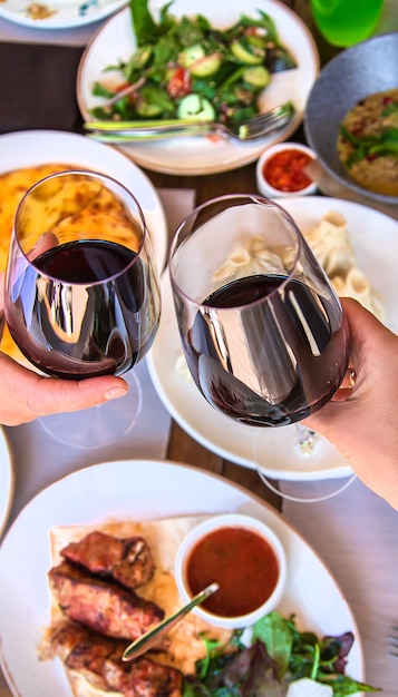 Comida de restaurante georgiano en el vino de mesa en las manos