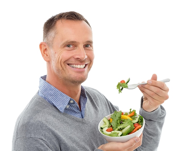 Foto comida de retrato y ensalada con un hombre en el estudio aislado en un fondo blanco comiendo verduras para la salud nutrición verde o dieta con un hombre maduro feliz interior para comer una comida orgánica para el bienestar