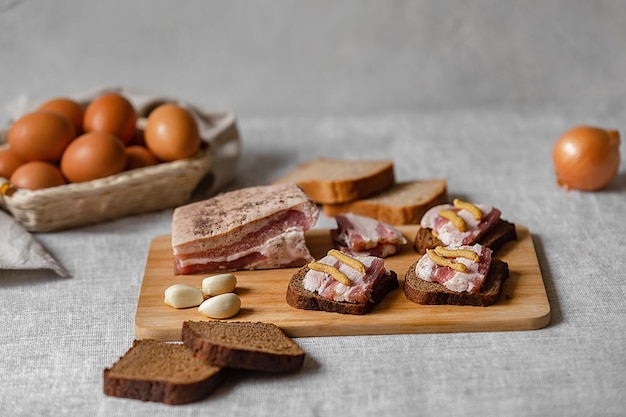 comida rústica, pão de centeio pronto e sanduíches de bacon com mostarda e ovos cozidos, cebola