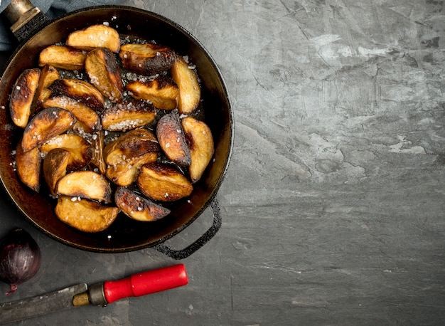 Comida rústica Patatas fritas en una sartén sobre una mesa de hormigón oscuro. Estilo rústico