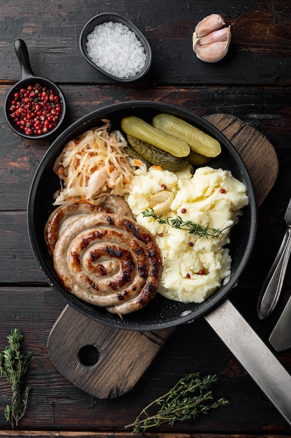 Comida rústica con puré de patatas salchicha asada y coles ácidas en sartén de hierro fundido