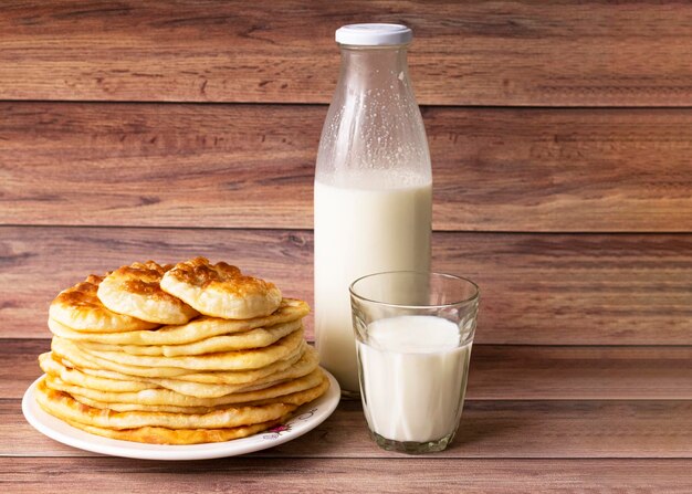 Comida rústica saludable Leche en una botella un vaso y tortas calientes para el desayuno Tortas de harina de trigo Fondo de madera