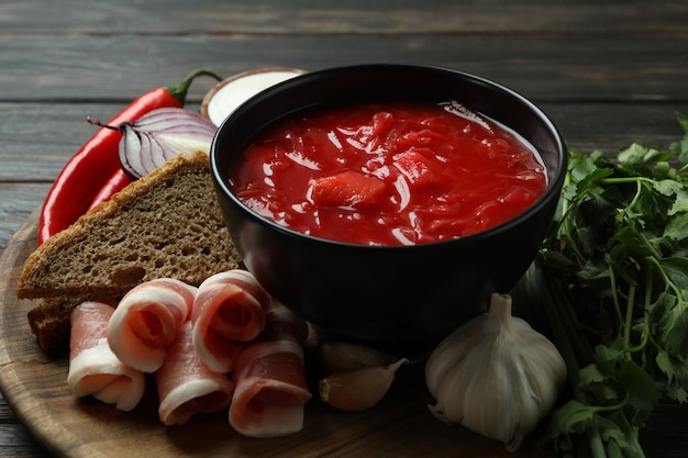 Comida saborosa com borscht e ingredientes em superfície de madeira