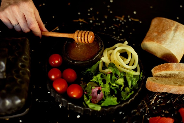 Comida saborosa e saudável Cerâmica artesanal de fundo preto A mão levanta uma colher para o mel O mel flui para baixo Cor bonita