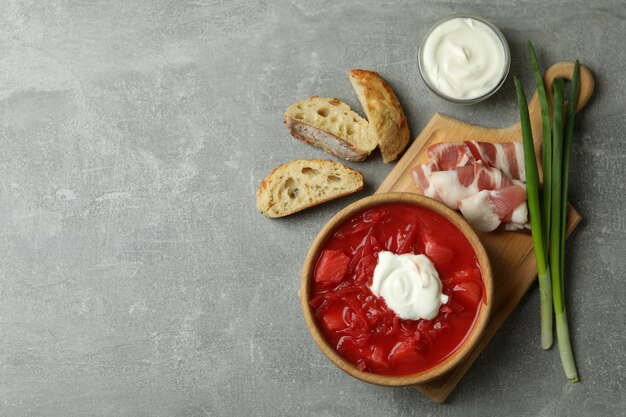 Comida sabrosa con borscht e ingredientes en mesa gris