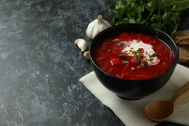 Comida sabrosa con borscht sobre superficie ahumada negra