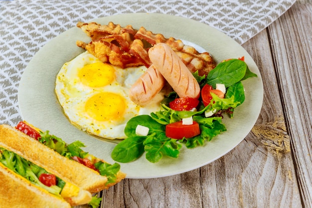 Comida sabrosa para huevos de desayuno, tocino, ensalada y sándwiches de queso a la parrilla.