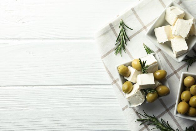 Comida sabrosa con queso feta sobre superficie de madera blanca