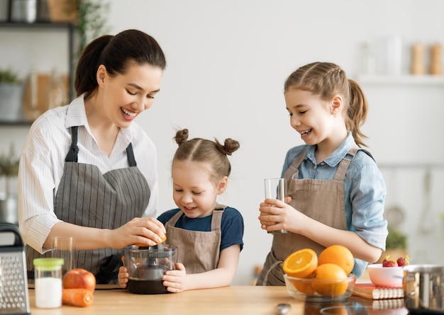 Comida saludable en casa Familia feliz en la cocina Madre e hijos están preparando jugo de naranja