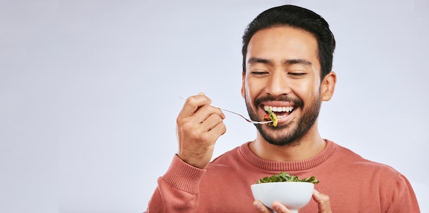 Comida saludable de frutas y un hombre asiático feliz en el estudio para el bienestar de la salud o la desintoxicación en el fondo gris Ensalada de desayuno y cara de hombre nutricionista sonriendo para una dieta limpia verde o cruda o un estilo de vida vegano