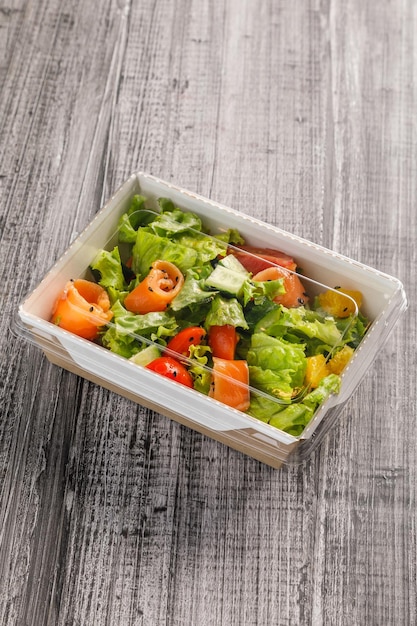 Comida saludable para llevar Ensalada con salmón pescado en contenedor para llevar