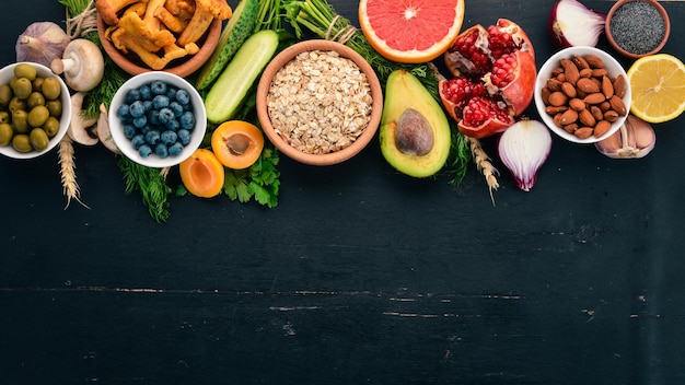 Comida saludable selección de alimentación limpia Verduras frutas nueces bayas y champiñones perejil especias Sobre un fondo negro Espacio libre para texto