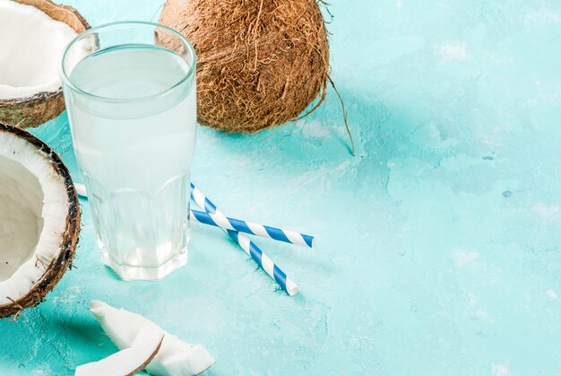 Comida sana . Agua de coco orgánica fresca con cocos, cubitos de hielo y menta, en azul claro,