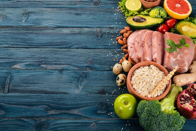 Comida sana. Carne cruda, aguacate, brócoli, vegetales frescos, nueces y frutas. Sobre un fondo de madera. Vista superior. Copie el espacio.