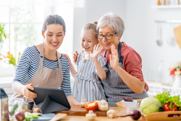 Comida sana en casa. Familia feliz en la cocina. La abuela, la madre y la hija del niño están preparando verduras.