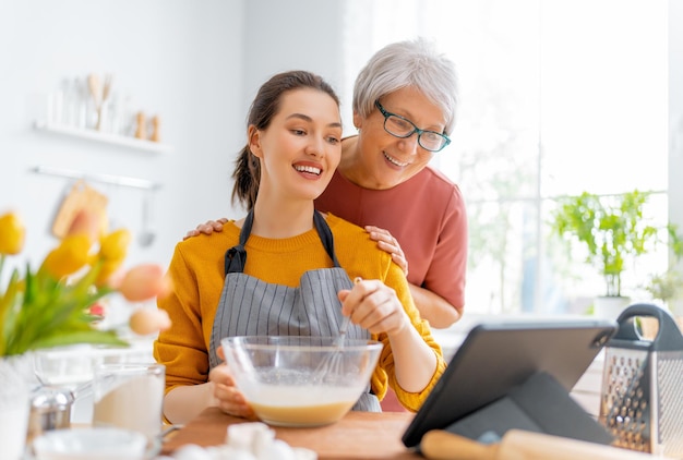 Comida sana en casa. Las mujeres felices están preparando pasteles en la cocina.