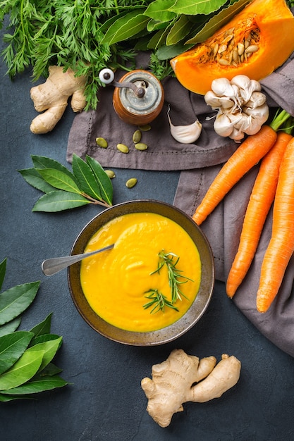 Comida sana, concepto de alimentación limpia. Vegetales de otoño picantes de temporada cremosa sopa de calabaza y zanahoria con ingredientes sobre una mesa. Fondo plano laico